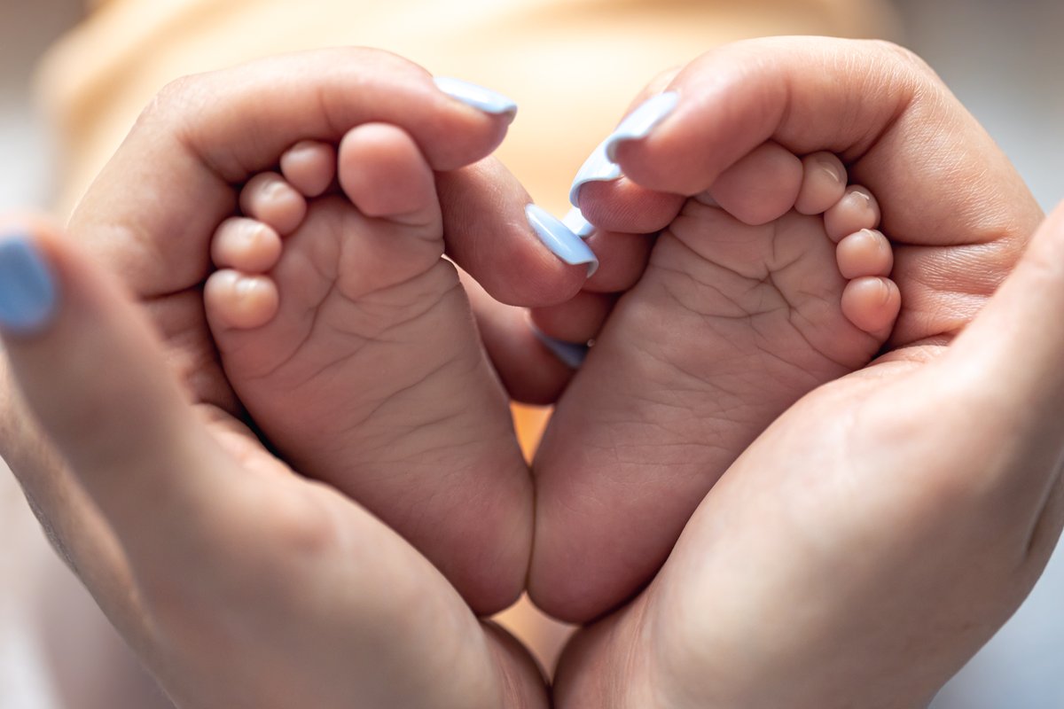 Babyfüße in den Händen einer Mutter, die ein Herz formen — Hoffnung im Kinderwunsch