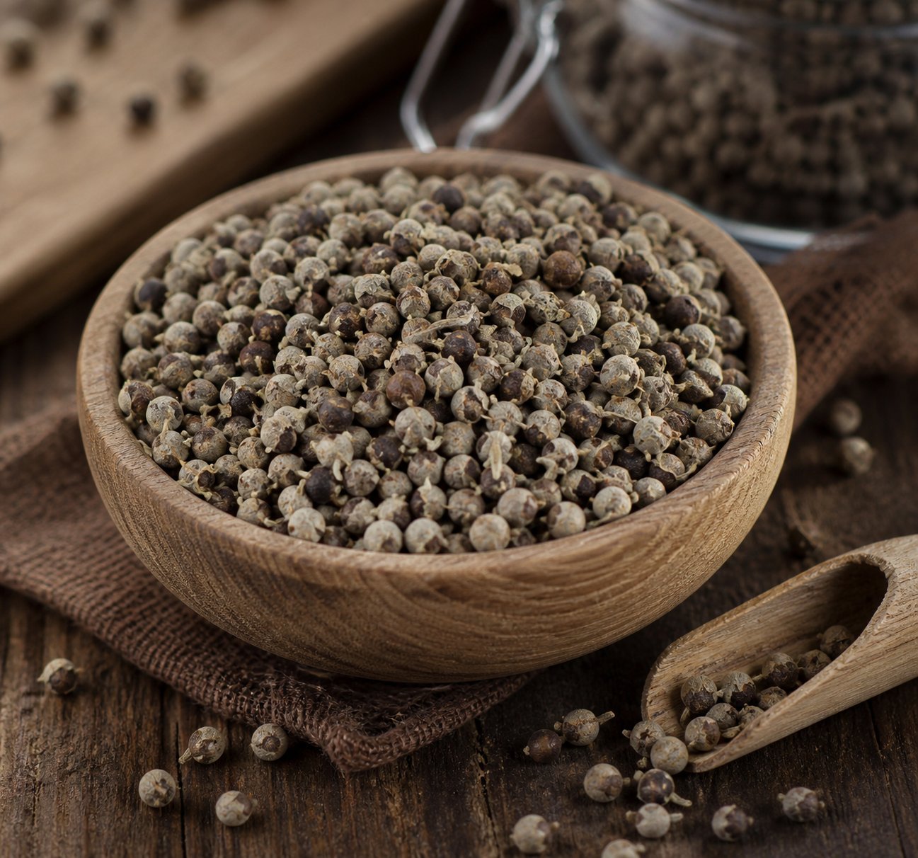 Mönchspfeffer-Beeren in einer Holzschale auf rustikalem Untergrund — die getrockneten Früchte der Heilpflanze Vitex agnus-castus