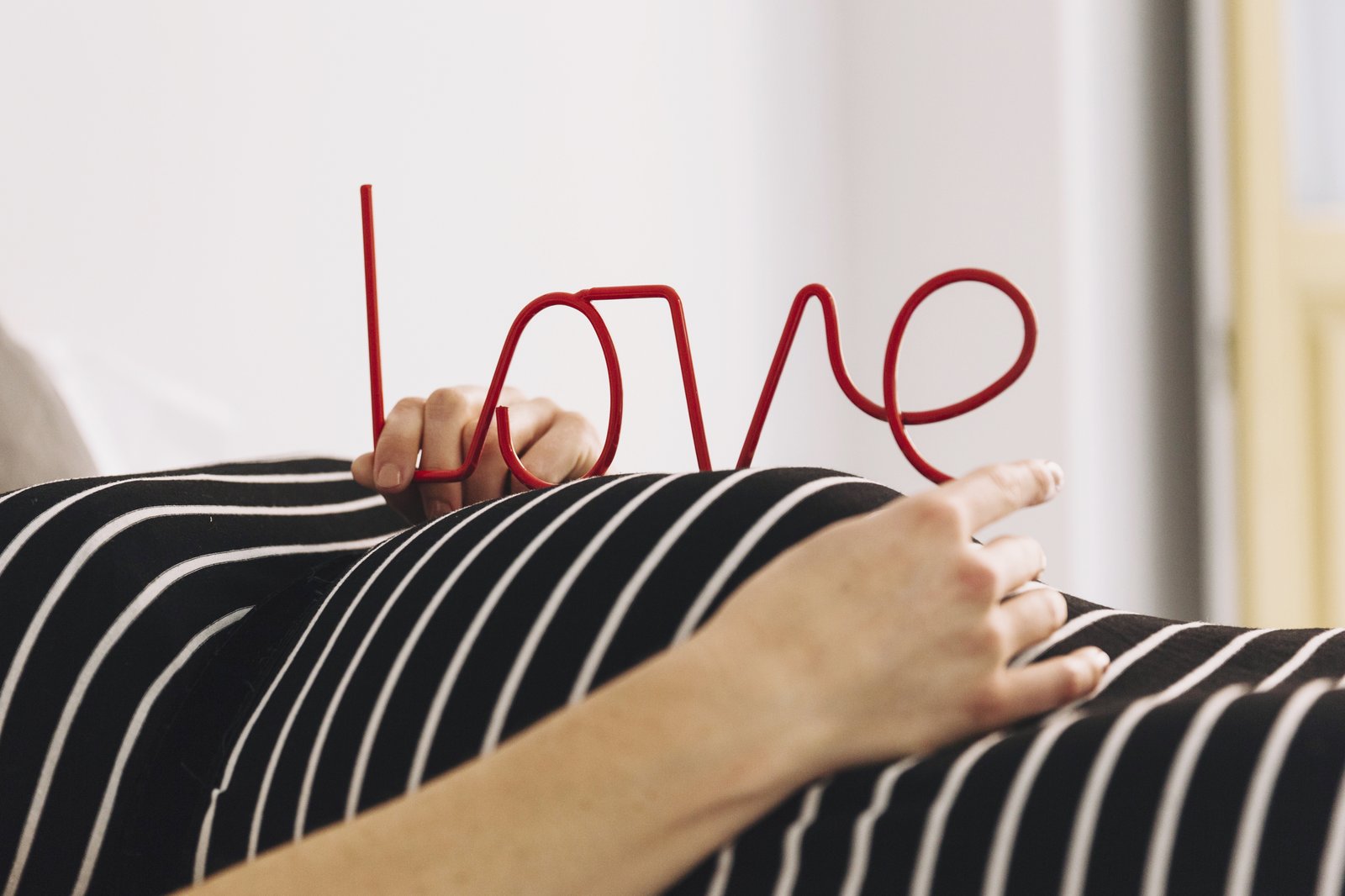 Schwangere Frau hält den Schriftzug „love