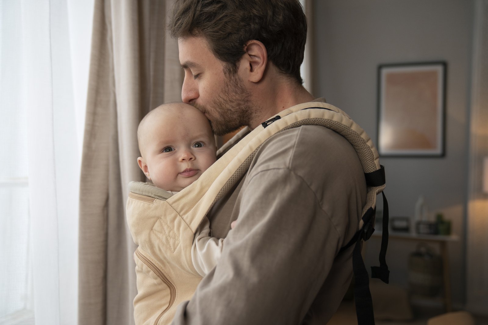 Vater trägt sein Baby in einer Komforttrage am Körper — Nähe und Bindung im Alltag